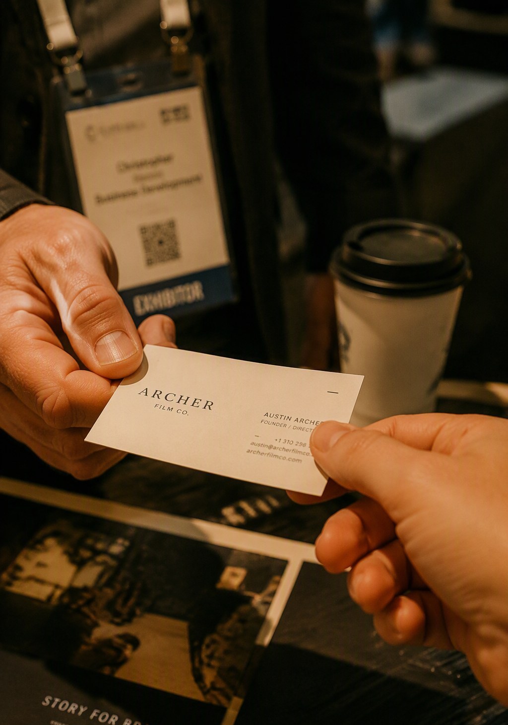Two hands exchanging a business card at an expo booth